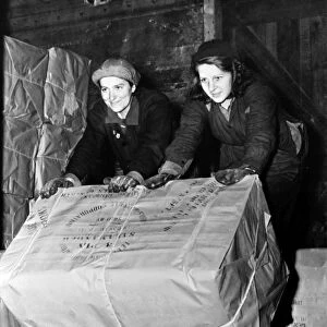 UNLOADING CARGO, 1943. Two women unloading bales of insulating material from the back of a truck