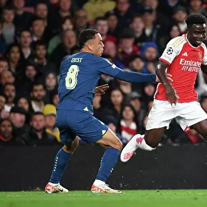 Arsenal's Bukayo Saka Fends Off PSV's Sergino Dest in Champions League Clash