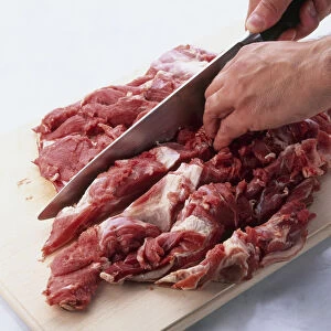 Boning leg of lamb using knife to cut through meat on either side of blade bone