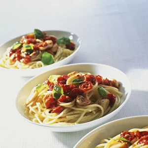 Three bowls of spaghetti topped with vegetables and herbs