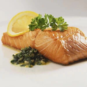 Cooked fish fillet, garnished with parsley, lemon slice and herb relish
