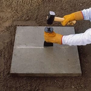 Cutting a paving slab, using a bolster and club hammer along a scored line