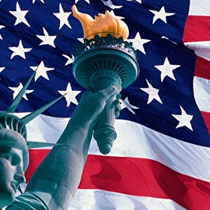This is a digitally created image of the American flag and Statue of Liberty. The head, arm and torch from the Statue is superimposed into the left hand side of the flag. The left hand side of the flag is ghosted back