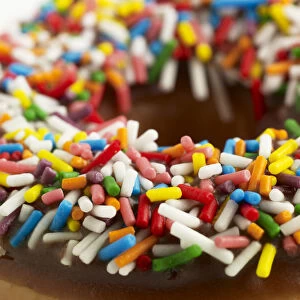 Doughnut with chocolate icing and colourful sprinkles, close-up