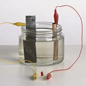 Early battery, working by chemical reaction, with zinc strip as negative electrode and copper strip as positive electrode, dipped into vinegar in glass jar