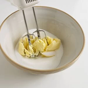 Electric whisk in mixing bowl with butter and flour