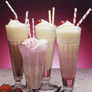 Four flavoured milkshakes served with straws, and fresh strawberries
