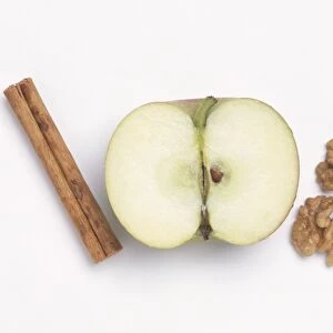 Halved apple, walnuts and cinnamon sticks