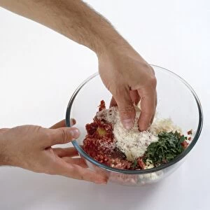 Hand mixing together meatball ingredients, minced beef, parsley, parmesan cheese and an egg in a glass bowl