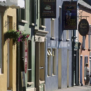 Ireland, County Kerry, Dingle, pedestrians in street lined with shops and cafes, facades painted pink and blue