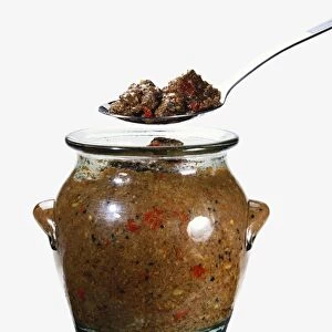 Jar of pickled venison and chillies and a spoon held above the jar