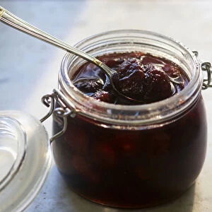 Jar of strawberry jam with spoon, close-up