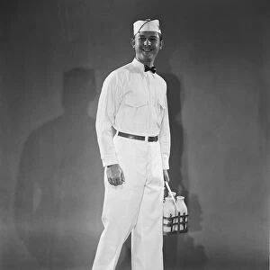 Milkman in uniform carrying a crate of milk