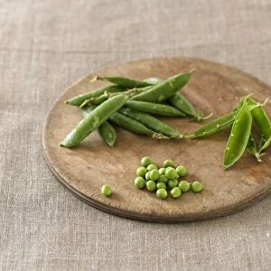 Pea pods and green peas on chopping board