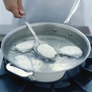 Person lifting poached egg from simmering water with slotted spoon