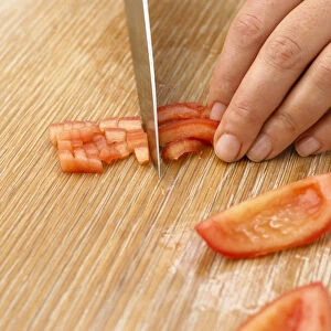 Person slicing tomato with knife