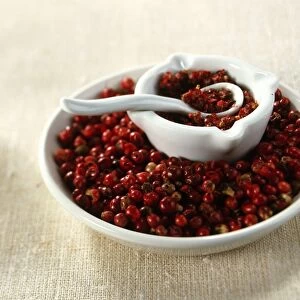 Pink Pepper (Schinus terebinthifolius), whole red berries in bowl and crushed in pestle