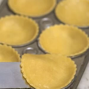 Placing pastry discs into the individual bases