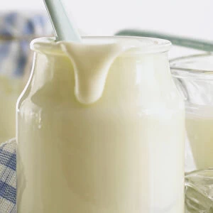 Plain yoghurt in a glass pot with a drip coming down the side
