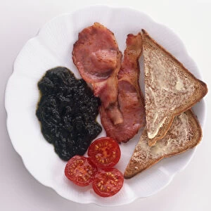 Plate of fried bacon, cherry tomatoes, slices of toast and laverbread made from seaweed, a traditional breakfast from Wales, view from above