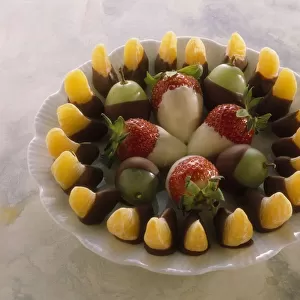 Plate of fruit dipped in chocolate, including tangerines and strawberries