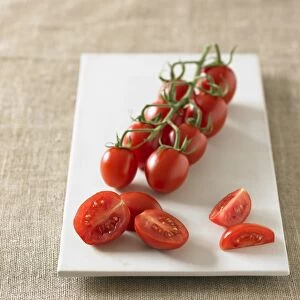 Plum tomatoes on vine and sliced on plate