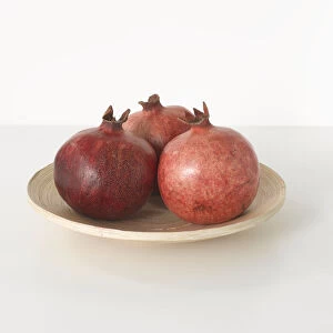 Three pomegranates on white plate