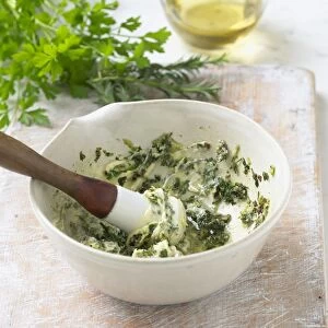 Preparing parsley and butter coating in bowl, using pestle, close-up