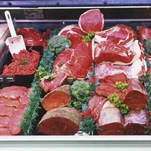 Red meats with herb garnish on display at meat counter