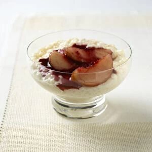 Rice pudding served with peach slices and raspberry in glass bowl