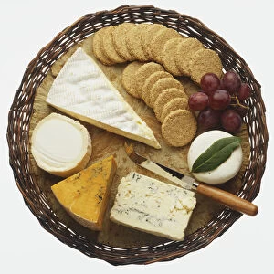 Selection of cheeses, oat biscuits and red grapes, served on a wicker tray, view from above
