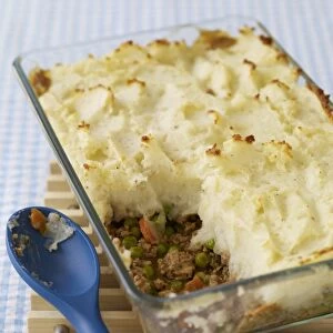 Shepherds pie in ovenproof glass dish, with spoon nearby