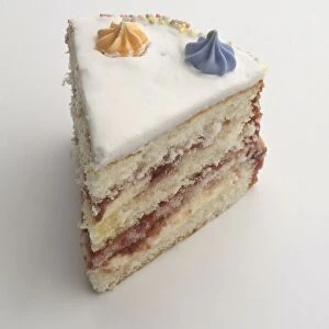 Slice of birthday cake filled with jam and buttercream and topped with icing, close-up