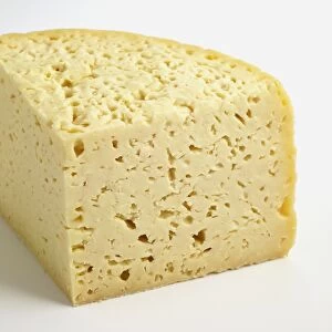 Slice of semi-soft Italian Pannerone cows milk cheese showing multiple holes