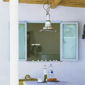 Snacks and drink bottles on a small table in roofed patio, looking into kitchen through open widow