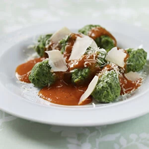 Spinach gnocchi with tomato sauce and parmesan shavings, on a plate