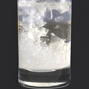 Sugar crystals on string in glass of translucent sucrose solution, close-up