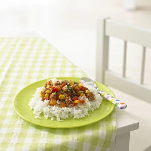 Sweet and sour pork with vegetables and rice on green plate, on checked tablecloth
