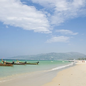 Thailand, Phuket, Ao Karon, beach at tourist resort with traditional boats moored at waters edge