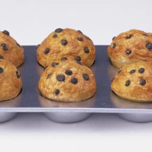 Tray of six baked muffins topped with raisins, high angle view