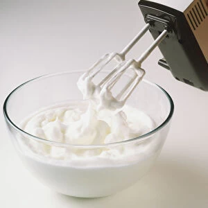 Using an electric hand mixer to whisk egg whites in a bowl