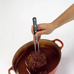 Using two pronged fork to test if silverside of beef in casserole dish in tender