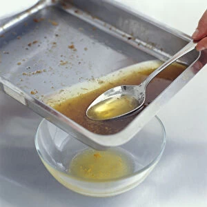 Using tablespoon to remove fat from roasting pan into glass bowl