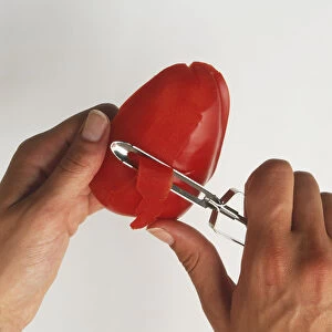 Using a vegetable peeler to remove the skin from a red pepper