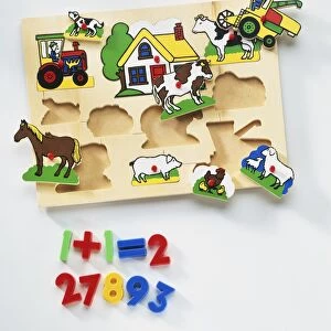 Wooden board with holes fitting shapes of farm animals, house and tractor, numbers from one to ten underneath