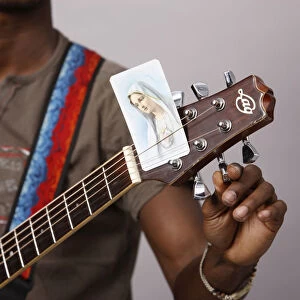 Young Christian man tuning a guitar