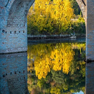 An archway of the Valentre Bridge in Cahors, France with the Lot River flowing underneath