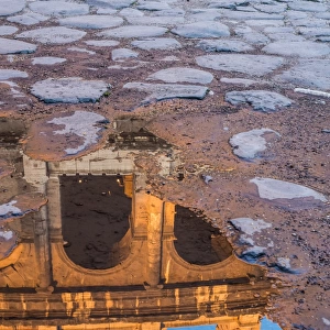 The Colosseum reflected in a puddle at sunrise in Rome, Italy
