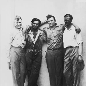 Four men with arms on each others shoulders, portrait (B&W)