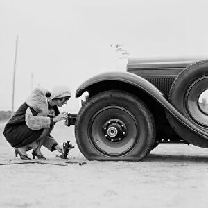 Woman changing flat tire on car